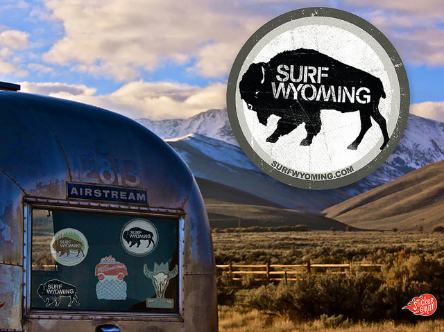 Surf-Wyoming-logo-sticker-with-Airstream-window-covered-with-custom-stickers-and-mountains-in-background