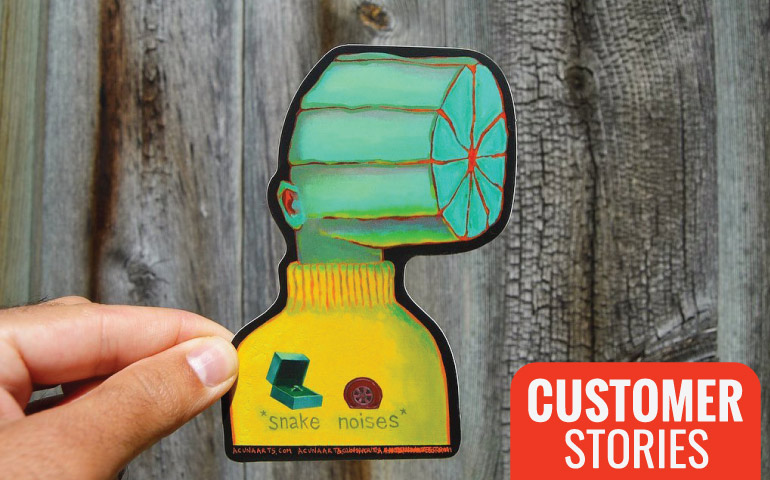 Hand-holding-Snake-Noises-Sticker-in-front-of-wood-fence-for-StickerGiant-Customer-Stories-blog