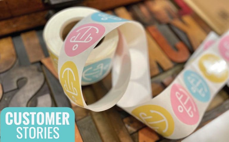 Custom roll labels with pastel pink, blue, and yellow branding applied on a label roll, showcasing custom product labels for packaging and retail applications.