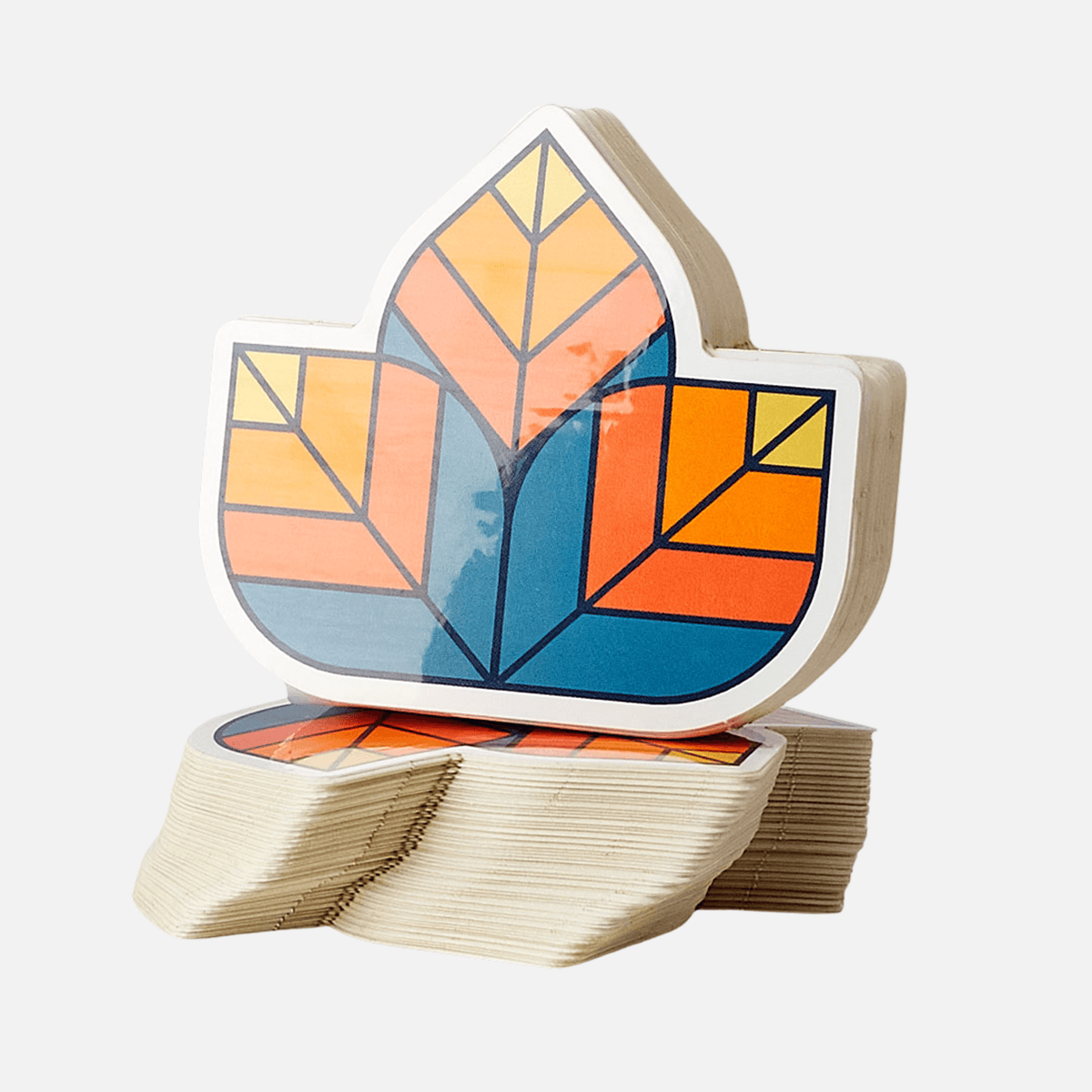 Stack of custom shape die cut stickers with a colorful geometric leaf design.